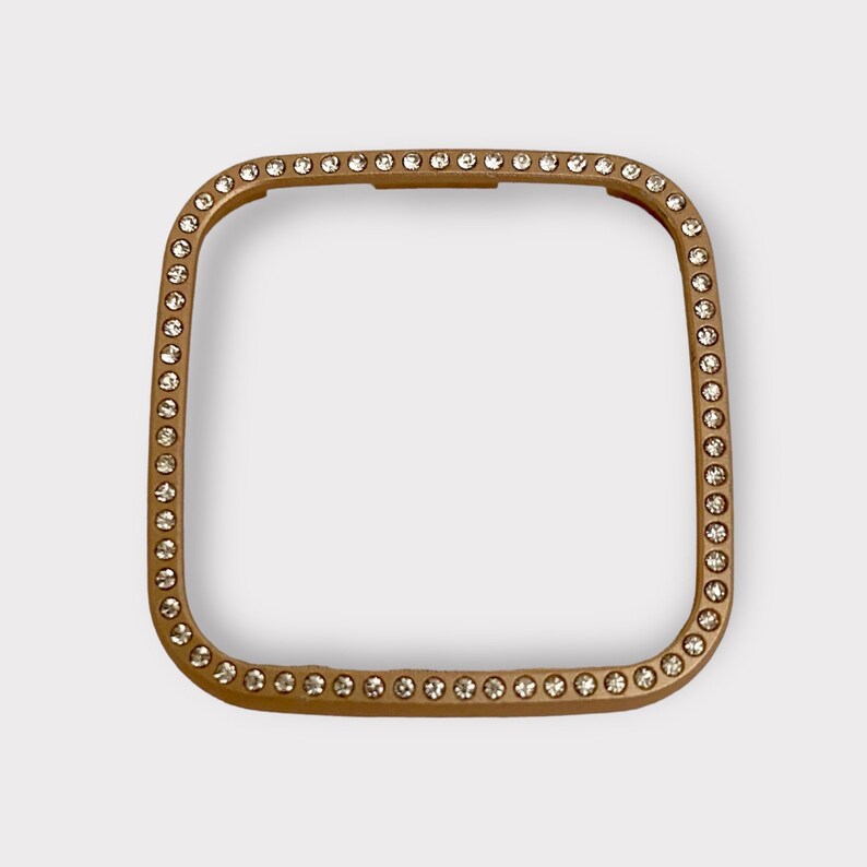 May include: A gold-toned square watch band with a clear rhinestone border.