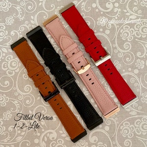 May include: Four different colored leather watch bands for the Fitbit Versa 1-2 Lite. The bands are brown, black, pink, and red.
