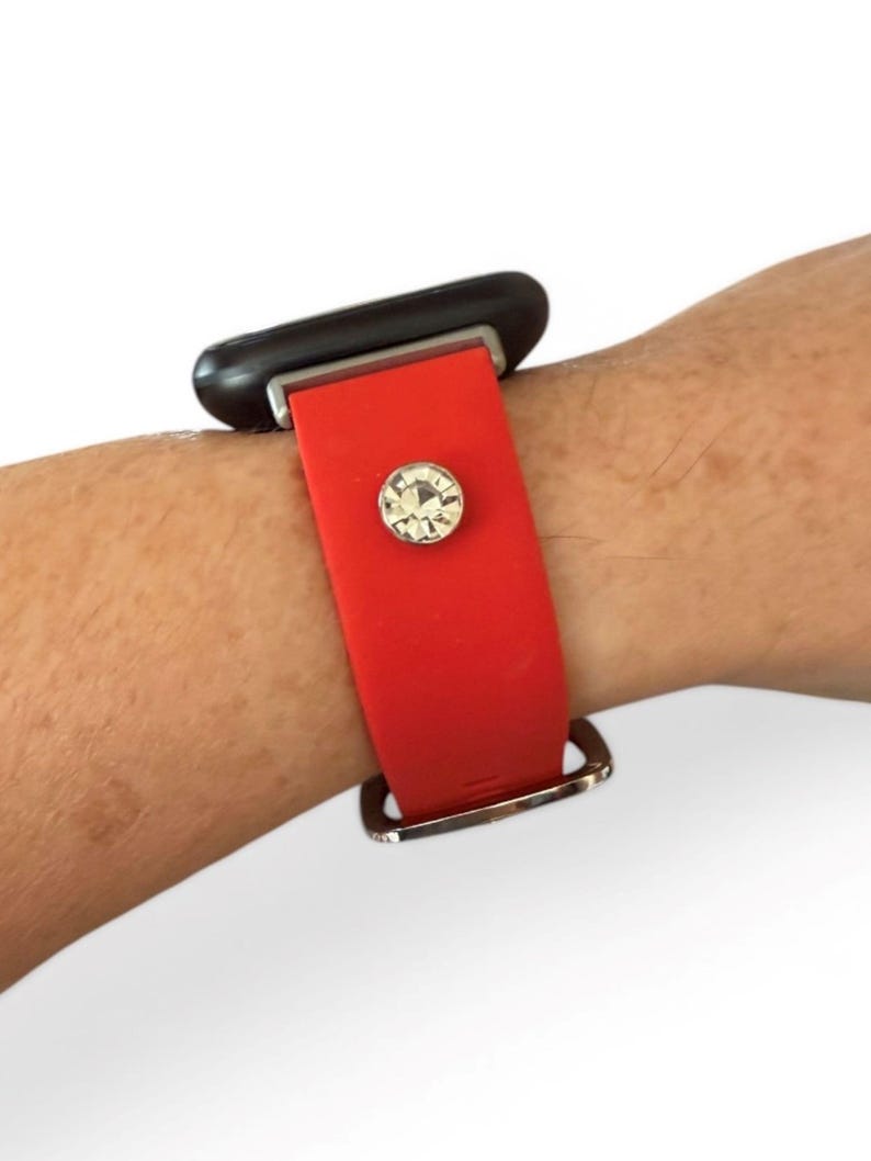 Peut inclure: Bracelet de montre rouge avec une boucle argent&eacute;e et un accent en cristal &eacute;tincelant. Le bracelet est fix&eacute; &agrave; un cadran de montre noir. La bande est faite d'un mat&eacute;riau souple.