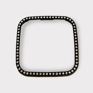 May include: Black square watch face cover with a border of clear rhinestones.