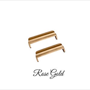 May include: Two rose gold metal watch band spring bars.
