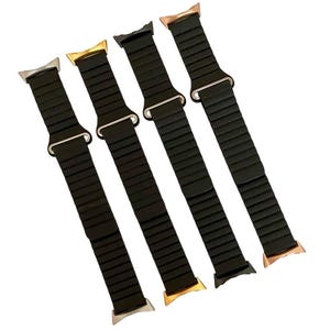 May include: Four black Apple Watch bands with different colored metal clasps. The bands are made of a flexible, ribbed material.
