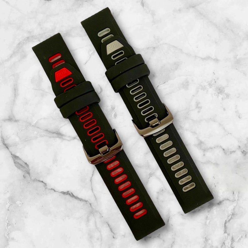Pu&ograve; includere: Due cinturini per orologio in silicone nero con fibbie argentate. Un cinturino ha accenti rossi e l'altro ha accenti argentati.