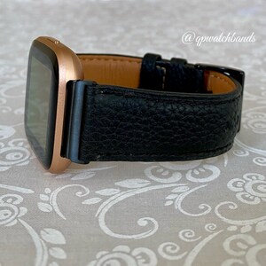 May include: A rose gold smartwatch with a black leather band. The band has a textured surface and a brown leather lining. The watch face is black and rectangular. The text "@gpwatchbands" is visible in the upper right corner of the image.