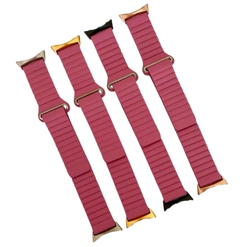 May include: Four pink silicone watch bands with gold and silver clasps. The bands have a ribbed texture.