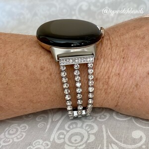 Pu&ograve; includere: Un cinturino per orologio argentato con quadrante nero e una tripla fila di strass trasparenti.
