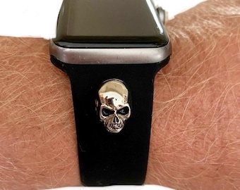 May include: A black Apple Watch with a silver band and a silver skull charm attached to the band.