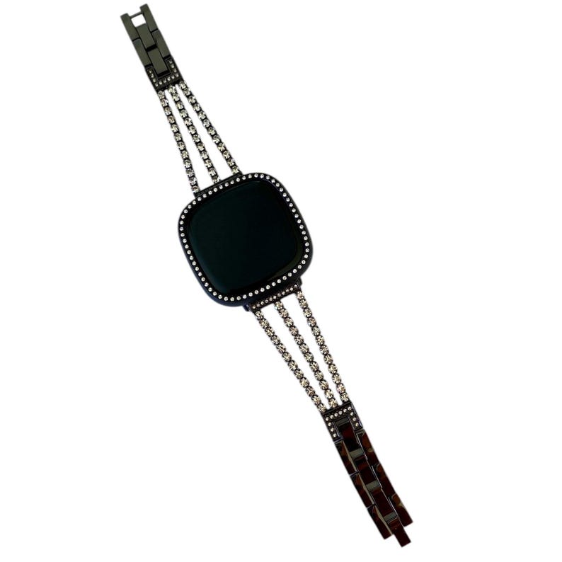 K&ouml;nnte beinhalten: Ein schwarzes Metallarmband mit schwarzem Zifferblatt und Strasssteinen. Das Armband hat drei Reihen Strasssteine.