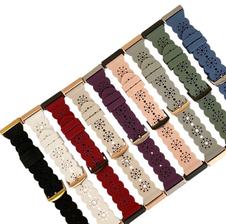 May include: A collection of colorful watch bands in various shades, including black, white, red, purple, pink, gray, green, and blue. Each band features a floral cutout design and a metal buckle. The bands are made of a flexible material.