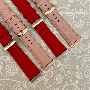 May include: Three watch bands in red, pink, and pink. The bands are made of leather and have a rose gold buckle. The bands are on a white background with a floral pattern.