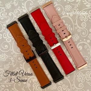 May include: Four different colored leather watch bands for a Fitbit Versa 3-Sense smartwatch. The bands are brown, black, red, and pink.