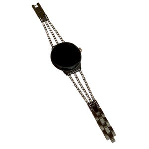 Pu&ograve; includere: Un orologio nero con quadrante nero e cinturino a catena argentato con strass.