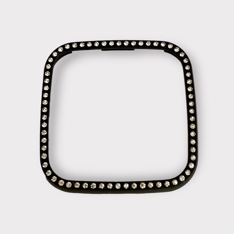 May include: Black square watch face cover with a border of clear rhinestones.