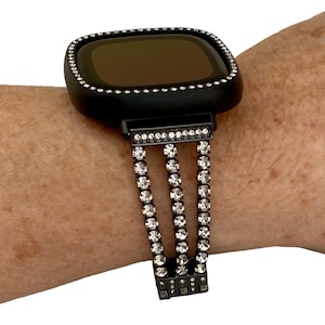 May include: A black smartwatch with a black rhinestone band. The watch face is black and the band has three rows of rhinestones.