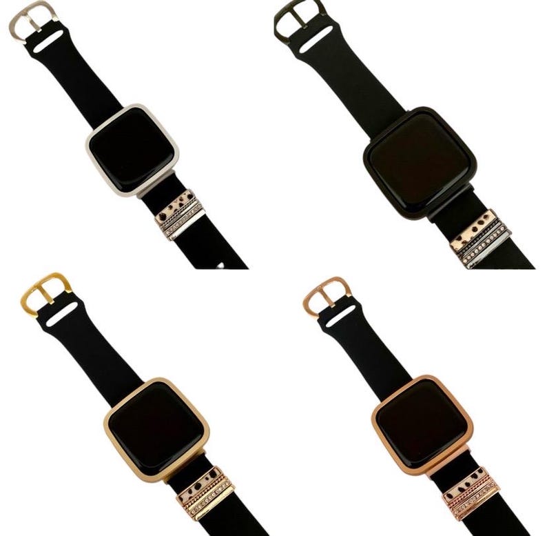 May include: Four different colored Apple Watch bands with decorative charms. The bands are black and the charms are silver, gold, and rose gold.