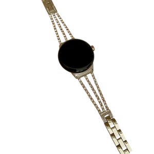 Pu&ograve; includere: Un orologio argentato con quadrante nero e cinturino a catena a tre file con strass.