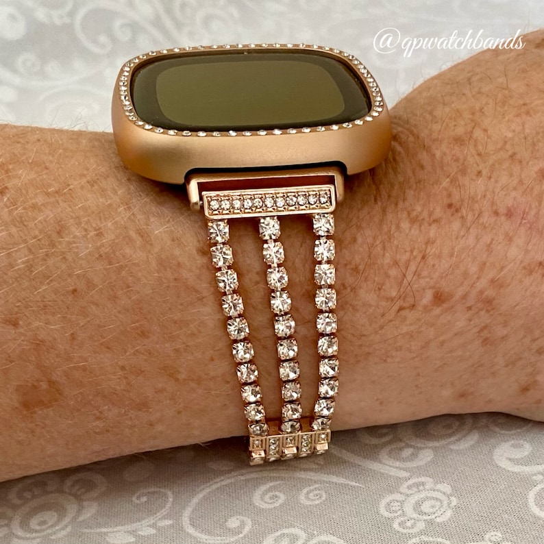 K&ouml;nnte beinhalten: Armband f&uuml;r eine Smartwatch in Ros&eacute;gold mit einer dreifachen Reihe aus klaren Strasssteinen. Das Armband ist f&uuml;r eine quadratische Smartwatch konzipiert.