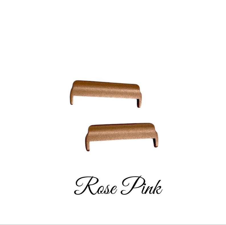 May include: Two rose gold metal watch band connectors. The connectors are shaped like a small couch.
