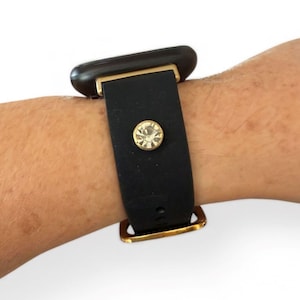 Peut inclure: Bracelet de montre noir avec des &eacute;l&eacute;ments dor&eacute;s et un bijou rond et transparent. Le bracelet est fait d'un mat&eacute;riau lisse et mat. Le bracelet est attach&eacute; &agrave; un cadran de montre fonc&eacute;.