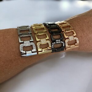 May include: Four different colored watch bands with a linked chain design and clear rhinestones. The bands are silver, gold, black, and rose gold.