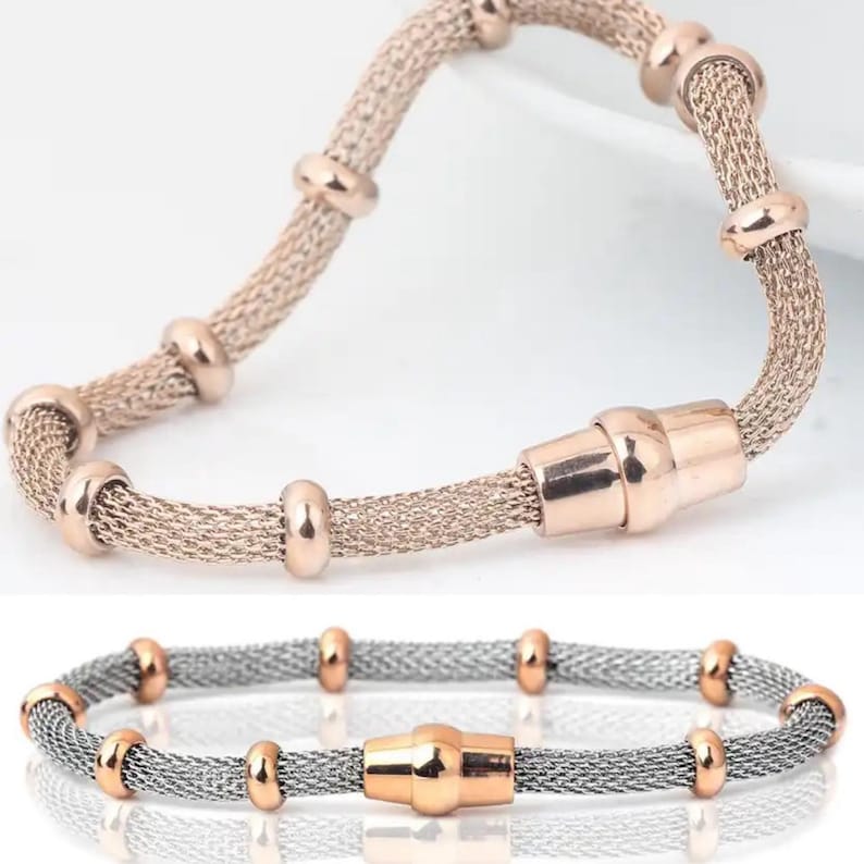 May include: Two bracelets. The top bracelet is rose gold with a mesh design and rose gold accents. The bottom bracelet is silver with rose gold accents. Both bracelets have a magnetic clasp.