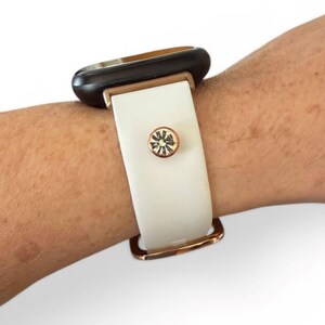 Peut inclure: Bracelet de montre blanc et dor&eacute; avec un cadran noir. Le bracelet est compos&eacute; d'un bracelet blanc avec une boucle dor&eacute;e et un accent en cristal. Le cadran de la montre est noir avec un cadre dor&eacute;.