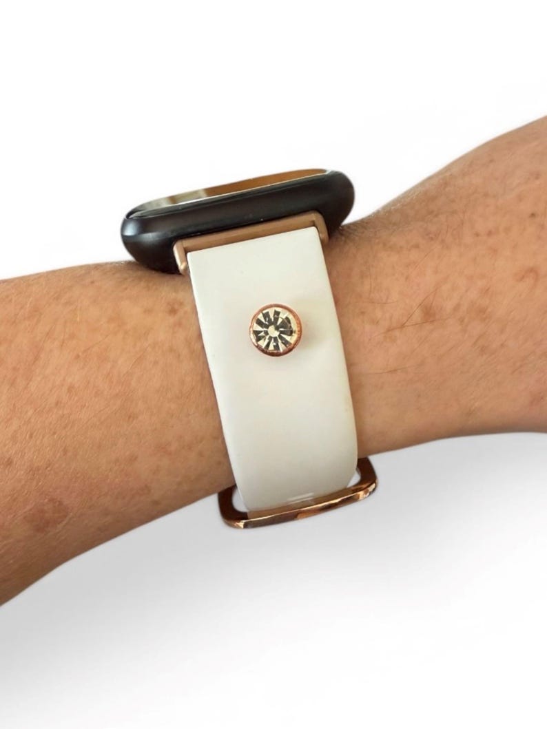 Peut inclure: Bracelet de montre blanc et dor&eacute; avec un cadran noir. Le bracelet est compos&eacute; d'un bracelet blanc avec une boucle dor&eacute;e et un accent en cristal. Le cadran de la montre est noir avec un cadre dor&eacute;.