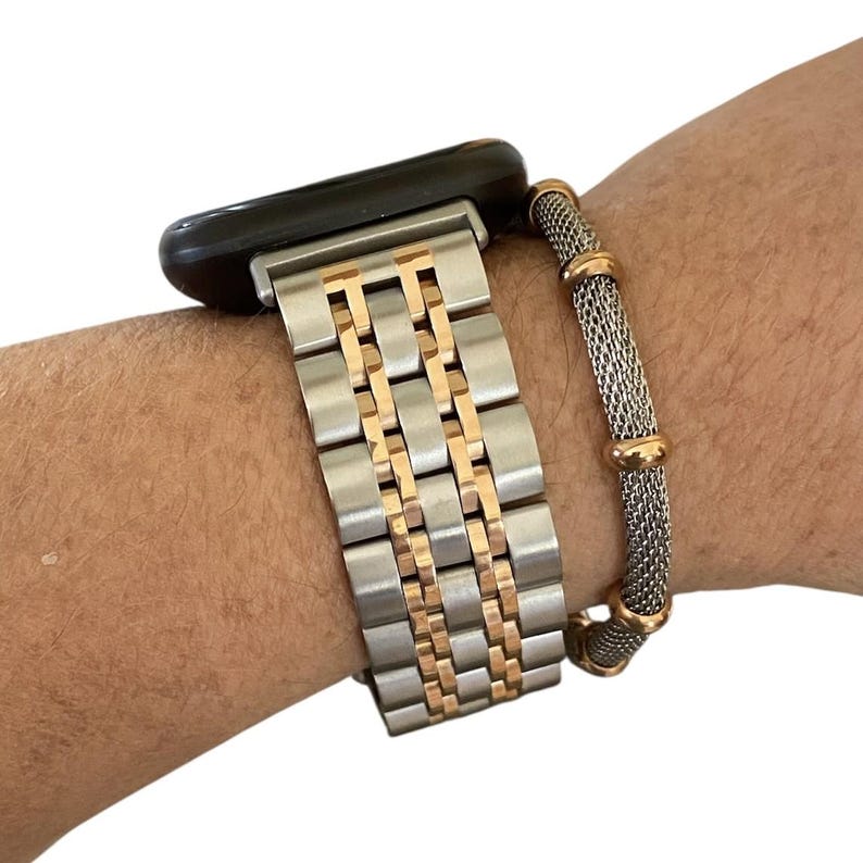 Peut inclure: Bracelet de montre argent&eacute; et dor&eacute; avec un bracelet assorti. Le bracelet de montre a un design &agrave; maillons rectangulaires avec des accents dor&eacute;s. Le bracelet est en maille argent&eacute;e avec des d&eacute;tails dor&eacute;s. La montre est noire.
