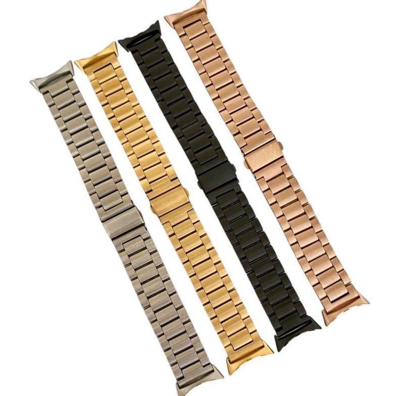 May include: Four metal watch bands in silver, gold, black, and rose gold. The bands are all the same style, with a classic link design.