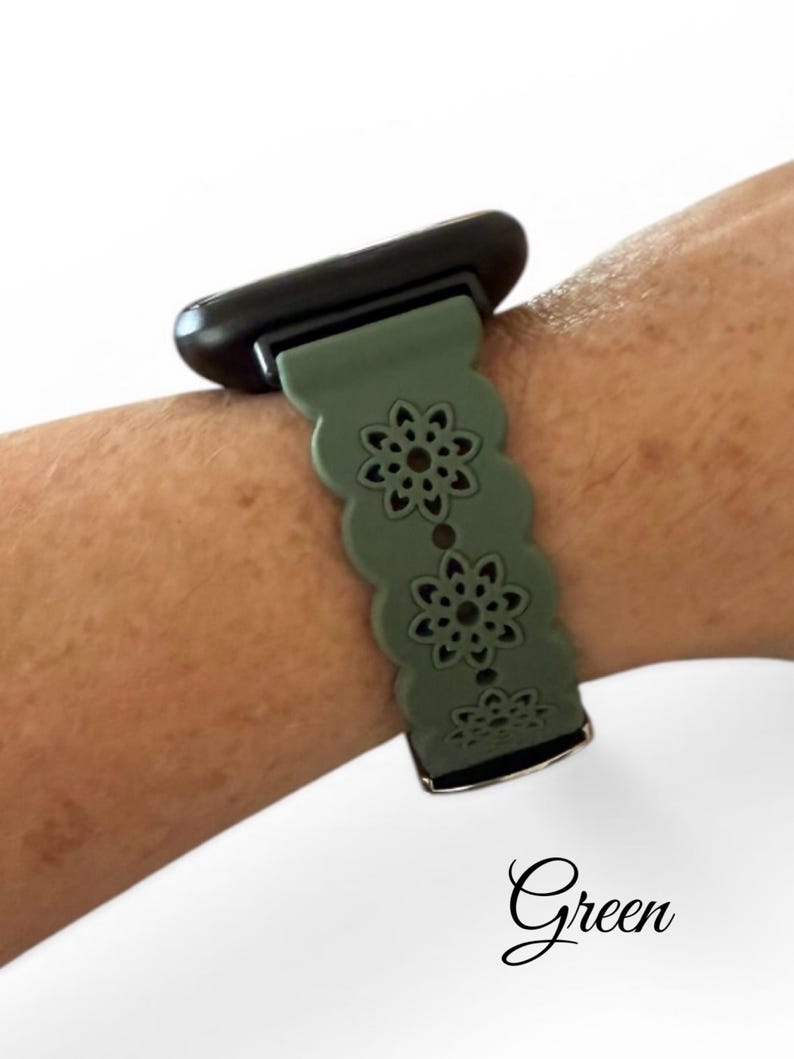 May include: A green watch band with a floral design is attached to a black watch face. The band is worn on a wrist. The word "Green" is written in cursive at the bottom of the image.