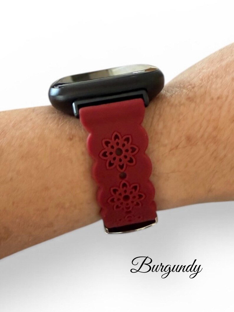 May include: Burgundy-colored smartwatch band with a floral design. The band is attached to a black smartwatch face. The word "Burgundy" is written in cursive at the bottom of the image.