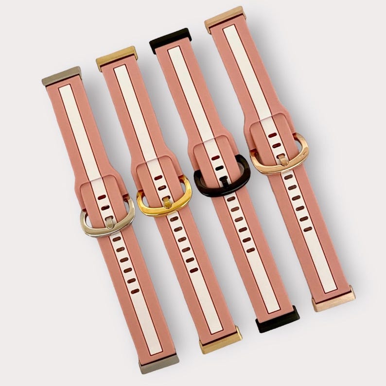 May include: Five pink silicone watch bands with white stripes and different colored metal buckles. The buckles are gold, silver, black, and rose gold.