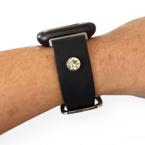 Peut inclure: Bracelet de montre en cuir noir avec une boucle argent&eacute;e et un grand cristal clair. Le bracelet est fix&eacute; &agrave; un cadran de montre fonc&eacute;. Le bracelet est port&eacute; au poignet.