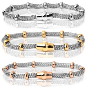 Peut inclure: Trois bracelets en maille avec fermoirs magn&eacute;tiques. Le bracelet sup&eacute;rieur a des accents argent&eacute;s, celui du milieu a des accents dor&eacute;s et celui du bas a des accents or rose. Les bracelets sont pr&eacute;sent&eacute;s sur une surface r&eacute;fl&eacute;chissante.