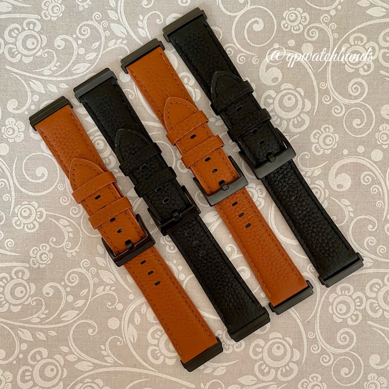 May include: Four watch bands, two black and two brown leather, with black metal clasps. The bands are arranged in a diagonal pattern on a white background with a floral design.