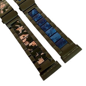 Puede incluir: Dos correas de reloj de metal negro con diferentes patrones de colores. Una correa tiene un patr&oacute;n de m&aacute;rmol azul y blanco, y la otra tiene un patr&oacute;n de m&aacute;rmol rosa y blanco.