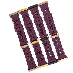 May include: Four plum-colored watch bands with floral cutouts and various metal clasps. The bands are made of a flexible material and feature a repeating flower pattern. The clasps are in silver, gold, and dark metal tones.
