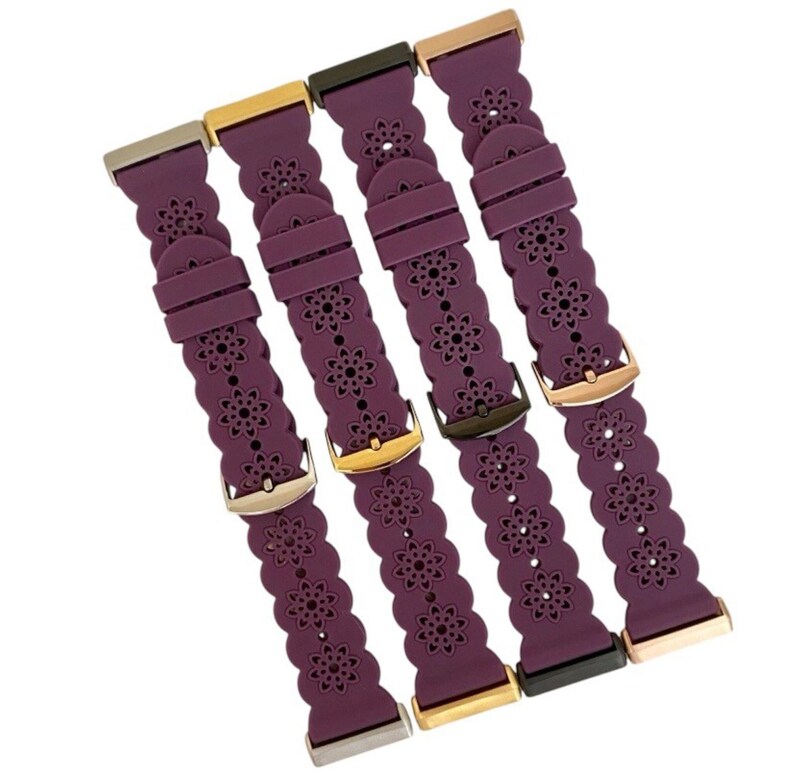 May include: Four plum-colored watch bands with floral cutouts and various metal clasps. The bands are made of a flexible material and feature a repeating flower pattern. The clasps are in silver, gold, and dark metal tones.