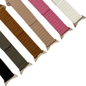 May include: Six different colored watch bands with a silver buckle. The bands are brown, beige, pink, white, gray, and black.