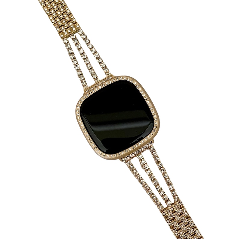 May include: A gold-tone watch band with a black face and a row of clear rhinestones around the edge. The band is made of multiple rows of rhinestones.