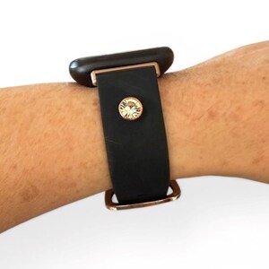 Peut inclure: Bracelet de montre noir avec des &eacute;l&eacute;ments dor&eacute;s et un accent en cristal. Le bracelet est fait d'un mat&eacute;riau lisse et mat. Le bracelet est attach&eacute; &agrave; une montre noire.