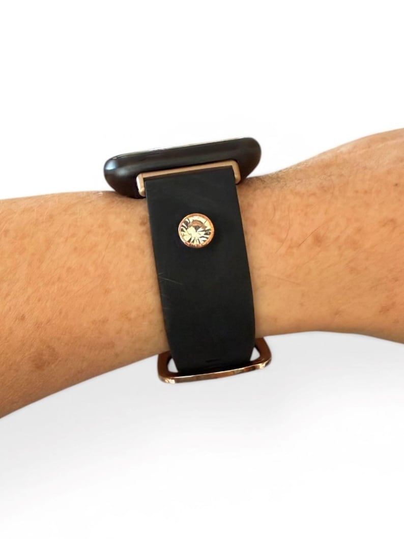 Peut inclure: Bracelet de montre noir avec des &eacute;l&eacute;ments dor&eacute;s et un accent en cristal. Le bracelet est fait d'un mat&eacute;riau lisse et mat. Le bracelet est attach&eacute; &agrave; une montre noire.