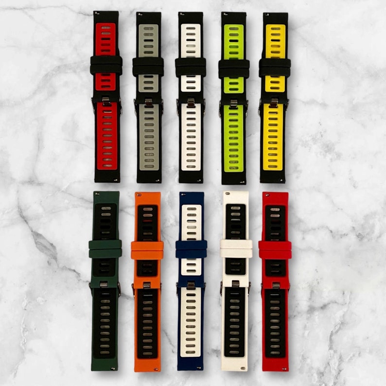 Pu&ograve; includere: Assortimento di 10 cinturini per orologi in silicone colorati. I cinturini sono neri con una striscia di colore a contrasto al centro. I colori includono rosso, grigio, bianco, verde, blu, arancione e giallo.