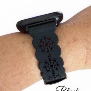 May include: Black smartwatch band with a floral cutout design. The band is attached to a black smartwatch. The word "Black" is written in cursive at the bottom of the image.