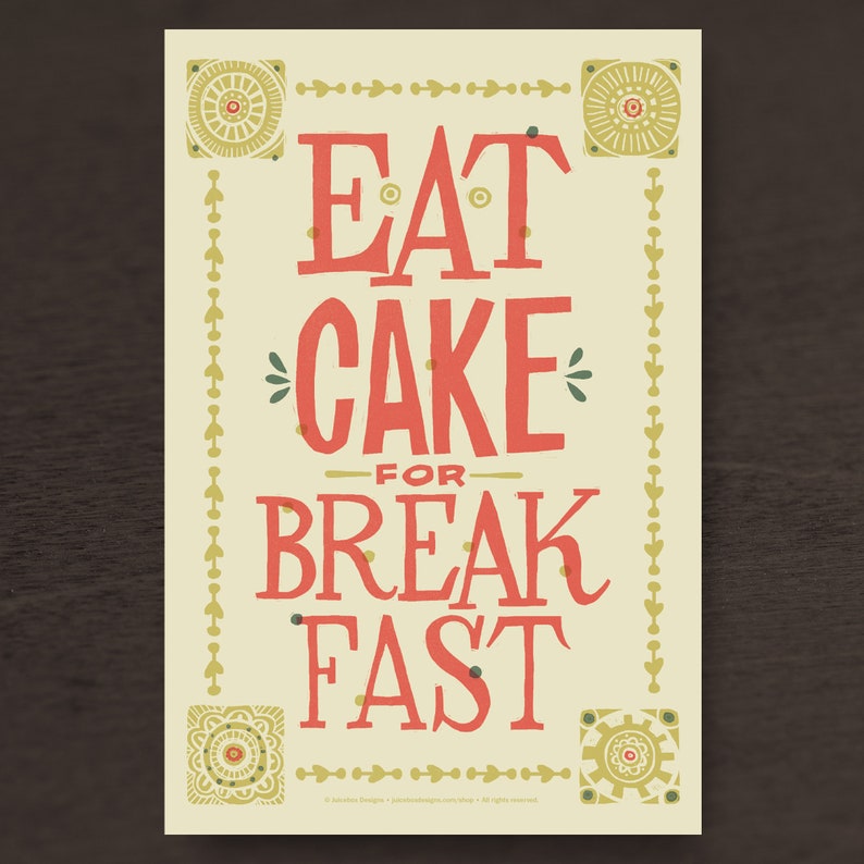 Może przedstawiać: Drukowany plakat w kolorze ż&oacute;łtym i białym z ozdobną ramką. Plakat zawiera napis "Eat Cake for Breakfast" w czerwonych i zielonych literach.
