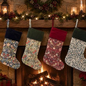 May include: Four Christmas stockings hanging in a row. The first has a dark blue cuff and floral pattern. The second has a dark green cuff and light floral print. The third has a red cuff and bird pattern. The fourth has a dark green cuff and leaf print.