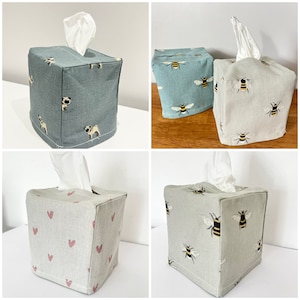 May include: Four different tissue box covers. One is blue with a pug dog pattern, one is light grey with a heart pattern, and two are light grey with a bee pattern.
