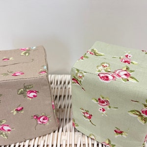 May include: Two fabric tissue box covers. One is beige with a floral pattern and the other is green with a floral pattern.