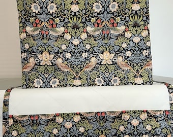 May include: A rectangular fabric cover featuring a dark navy background with a repeating pattern of birds, strawberries, and floral motifs in shades of green, cream, and red. The cover includes a solid white quilted section across the middle.