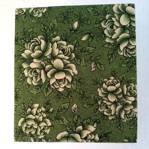 May include: A green square tile with a white floral pattern. The tile features a repeating pattern of white roses with green leaves on a green background.